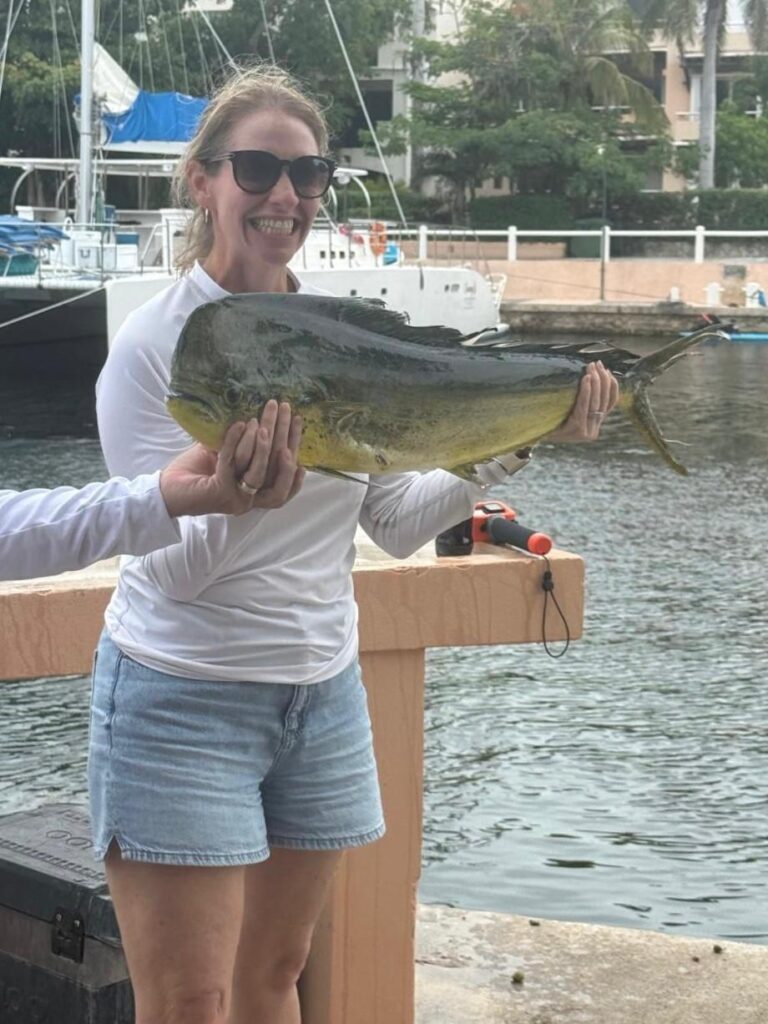 Guest holding a mahi-mahi at the Puerto Aventuras marina after a 6-hour private fishing charter, Riviera Maya