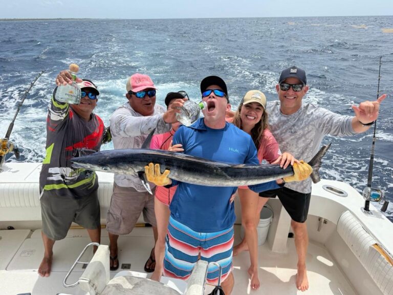 Guests and crew celebrating a wahoo catch with tequila shots on a private fishing charter out of Puerto Aventuras