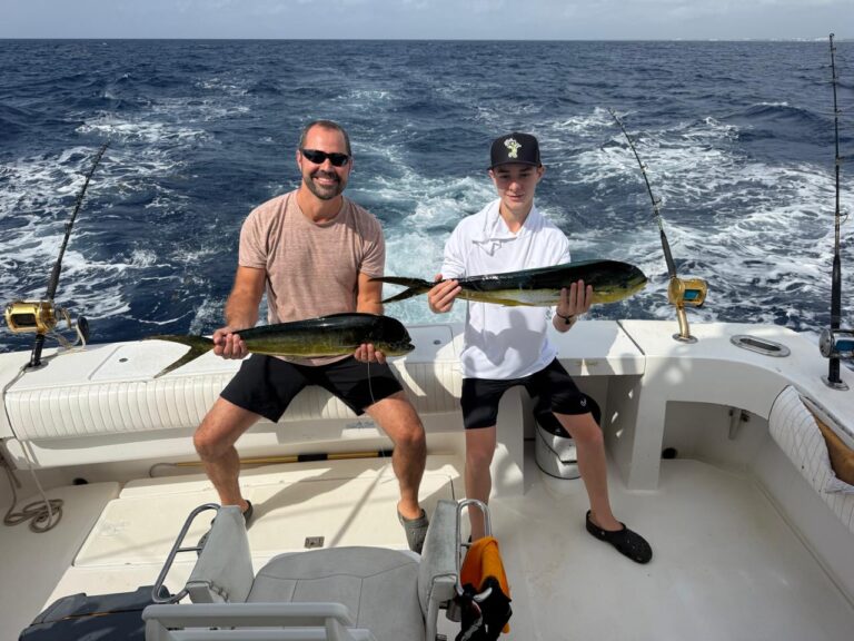 Guests holding mahi-mahi on a private fishing charter out of Puerto Aventuras, Riviera Maya