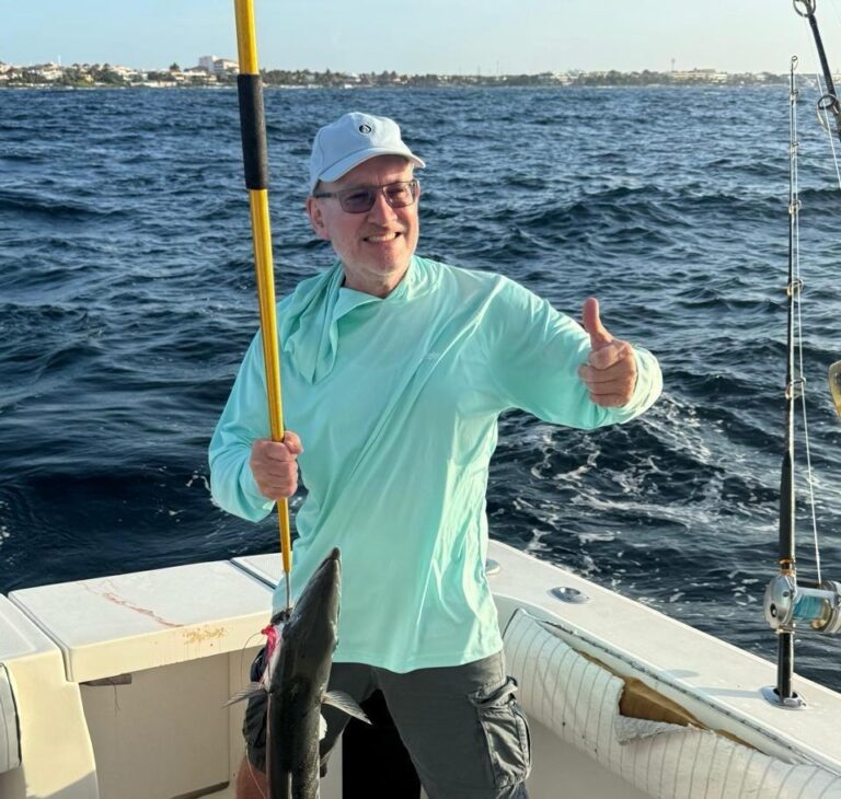 Guest holding a barracuda caught on a 4-hour private fishing charter out of Puerto Aventuras, Riviera Maya